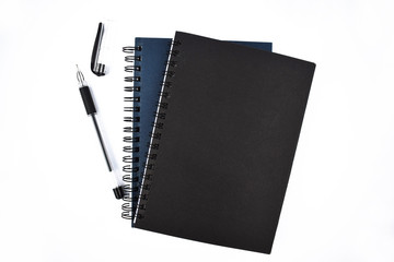 Bunch of blue and black colored note book diary and one black colored ball point pen placed together
