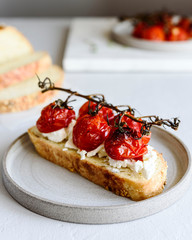 Tomato confit and goat cheese bruschetta on grey concrete table. Selective focus