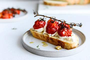 Tomato confit and goat cheese bruschetta on grey concrete table. Selective focus