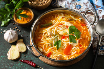 Tukpa soup Indian cuisine. Hot noodle soup with chicken ginger, cilantro and garlic in a bowl on a dark tabletop.