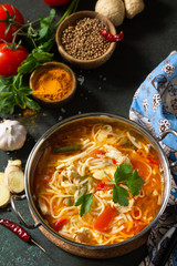 Tukpa soup Indian cuisine. Hot noodle soup with chicken ginger, cilantro and garlic in a bowl on a dark tabletop.