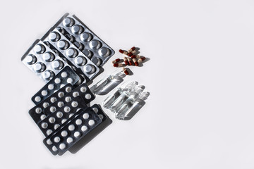Medicines: white plain breakable tablets in transparent sticks, in metal non-trasparent sticks, overencapsulated tablets, ampuls with anti-virus vaccine on white background. Copy space.