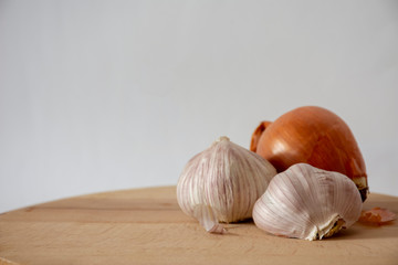 Onion and garlic on a wooden board with a white background