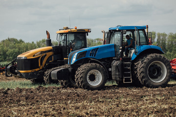 yellow and blue tractor stand in a field during a test drive demonstrating power