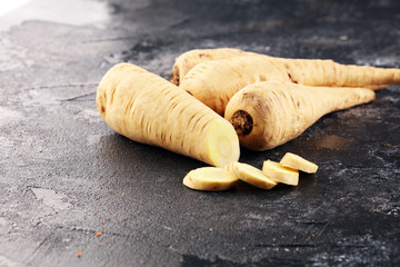 Parsnip root and slices on rustic background. Fresh raw organic parsnip - obrazy, fototapety, plakaty