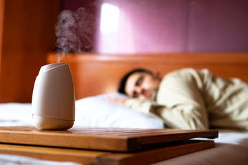 Air freshener taking out perfume in the bedroom with a sleeping man.