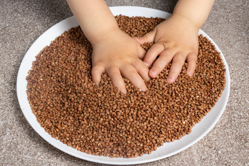 
A child plays with buckwheat. Games for the development of fine motor skills of children, games with various cereals.