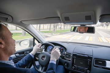 Middle age businessman in a blue suit and rubber gloves for protect himself from bacteria and virus driving a car. Coronavirus. Pandemic.