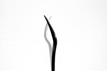 White and black plastic forks on a white background. Forks stand sideways, connected by teeth.