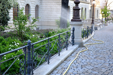 path of granite cobblestones decorative black fence at the edge of flowerbed gardener let water...