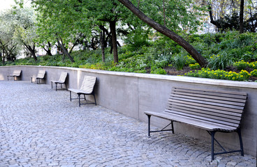  wooden bench near the edge of the path in the park pedestrian blocks pavement retaining wall low...