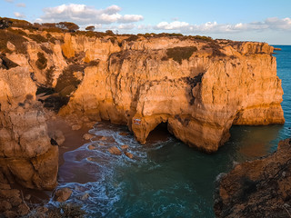 Panoramic view near Praia dos Arrifes on Algarve coast, Albufeira, Portugal. Calm turquoise bay, high rock cliffs with danger sign and small empty beach. Tourism and travel concept.