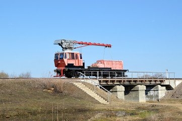 Fototapeta premium Red railroad crane on the bridge in countryside