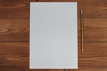 Blank paper and ordinary pencil on a wooden table. View from above