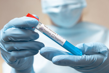Coronavirus vaccine, positive. Doctor in protective suit, medical mask and latex gloves holds a...