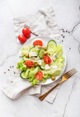 Greek salad with feta cheese, fresh vegetables and olives on white rustic background top view