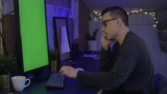 The guy at home sits at the computer and works or plays games behind a blue, green screen. The guy at home works as a freelancer and speaks on the phone, gets angry, speaks barefoot, is nervous, rude