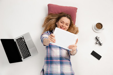 Young caucasian woman using devices, gadgets isolated on white studio background. Concept of modern...
