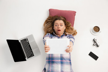 Young caucasian woman using devices, gadgets isolated on white studio background. Concept of modern...