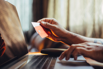 Mockup shot of man's hand with tattoos holding  credit card with blank screen in the house for shopping. Shopping at home.
