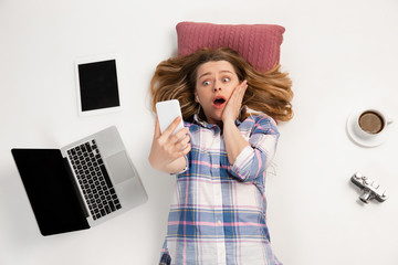 Young caucasian woman using devices, gadgets isolated on white studio background. Concept of modern...