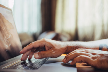 A man shopping by using laptop computer at home. Male hand typing on laptop keyboard in office. Businessman, student, work from home, distance education, online learning, studying concept