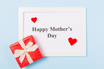 White picture frame with text Happy Mother's Day , gift box and red heart on light blue background . Happy Mother's Day concept.