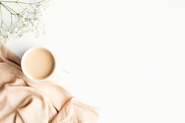 Morning cup of coffee with blanket and flower on white wooden background. Flat lay, top view, copy...