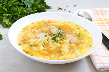 Dietary chicken soup with fusilli in a white bowl on a light background