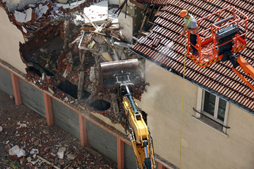 Démolition d'une habitation par un engin de chantier.