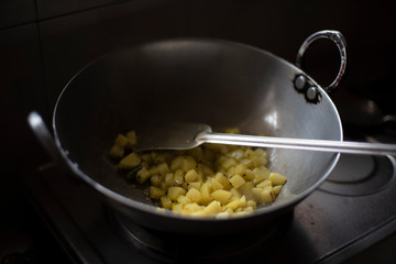 Indian spicy potato curry being cooked in a large aluminium utensil in an Indian kitchen during lock-down. Indian food.