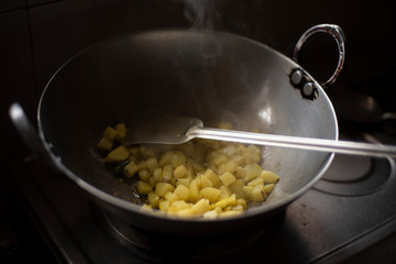 Indian spicy potato curry being cooked in a large aluminium utensil in an Indian kitchen during lock-down. Indian food.
