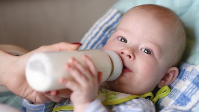 Mother feeds the baby from the bottle