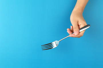 Female hands hold a fork on blue background