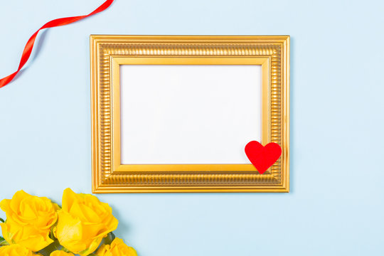 Golden frame empty blank picture and yellow roses on light blue background . Copy space free space for text. Holiday card concept. Mock up. Greeting. Mother's Day. St Valentine's Day. Love .