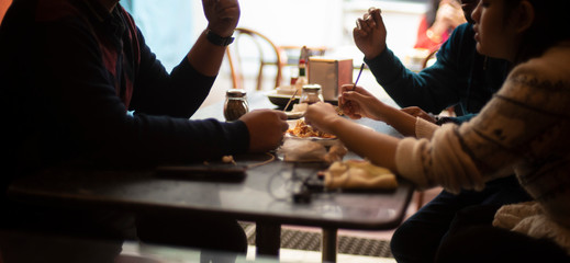 Silhouette of a group of young friends having lunch in a restaurant in a festive day. Indian...