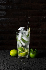 Fresh mojito with splash in the top and dark brick background