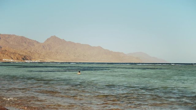 Man snorkeling in red sea, Beautiful landscape of blue sea and clear sky, waves in the sea and mountains on horizon Egypt, Dahab, slow motion, full hd