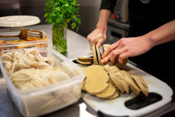 Homemade seitan being sliced to prepare vegan meals in a vegan and vegetarian cafe