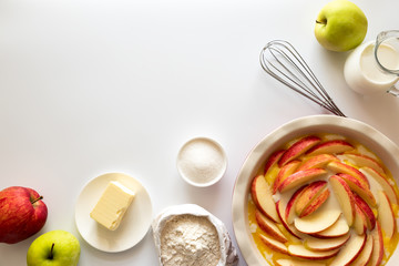 Ingredients for making apple cake. Flour, sugar, butter, milk and fresh apples on white wooden background. Top view. Flat lay