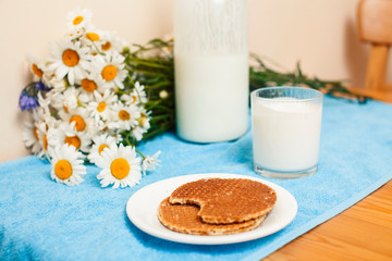 Fototapeta na wymiar Simply stylish wooden kitchen with bottle of milk and glass on table, summer flowers camomile, healthy foog moring concept