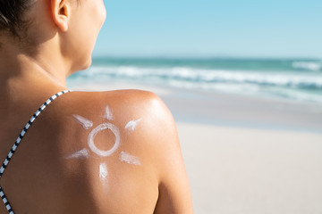 Woman with sun shaped sunscreen on shoulder