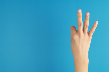right hand a woman show the third, number three sign on blue background