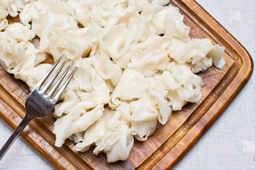 Ravioli for borscht. Wooden cutting desk texture. Grandmas recipe homemade preparation food background. Polish christmas meal ingerdient called uszka that are added to soup called barszcz.
