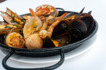 Sauteed shellfish and seafood in a black pan on a white background 