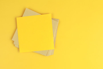 A yellow paper note on a stack of recycle brown papers on yellow background. Business concept.