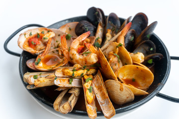Sauteed shellfish and seafood in a black pan on a white background 