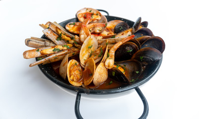 Sauteed shellfish and seafood in a black pan on a white background 