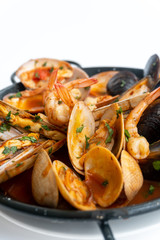 Sauteed shellfish and seafood in a black pan on a white background 