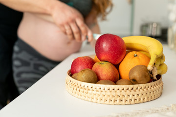 Pregnant woman with fruits in the kitchen